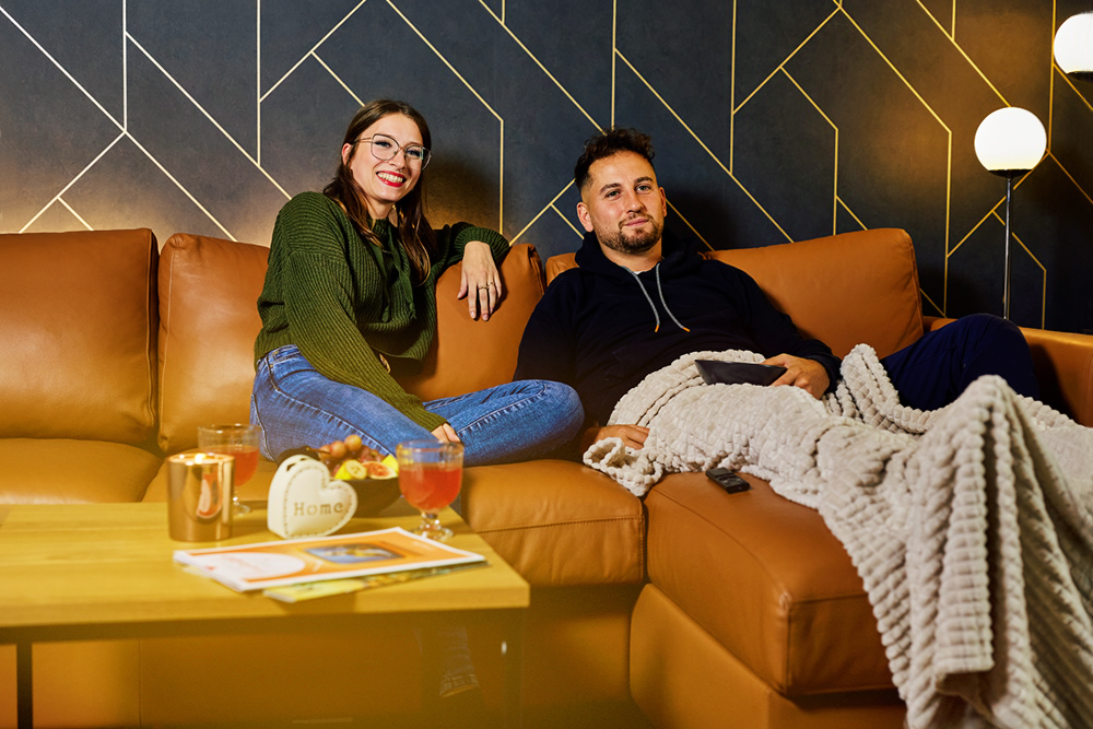 Man und Frau sitzen gemeinsam auf der Couch und schauen TV mit ihrem neuen Glasfaseranschluss