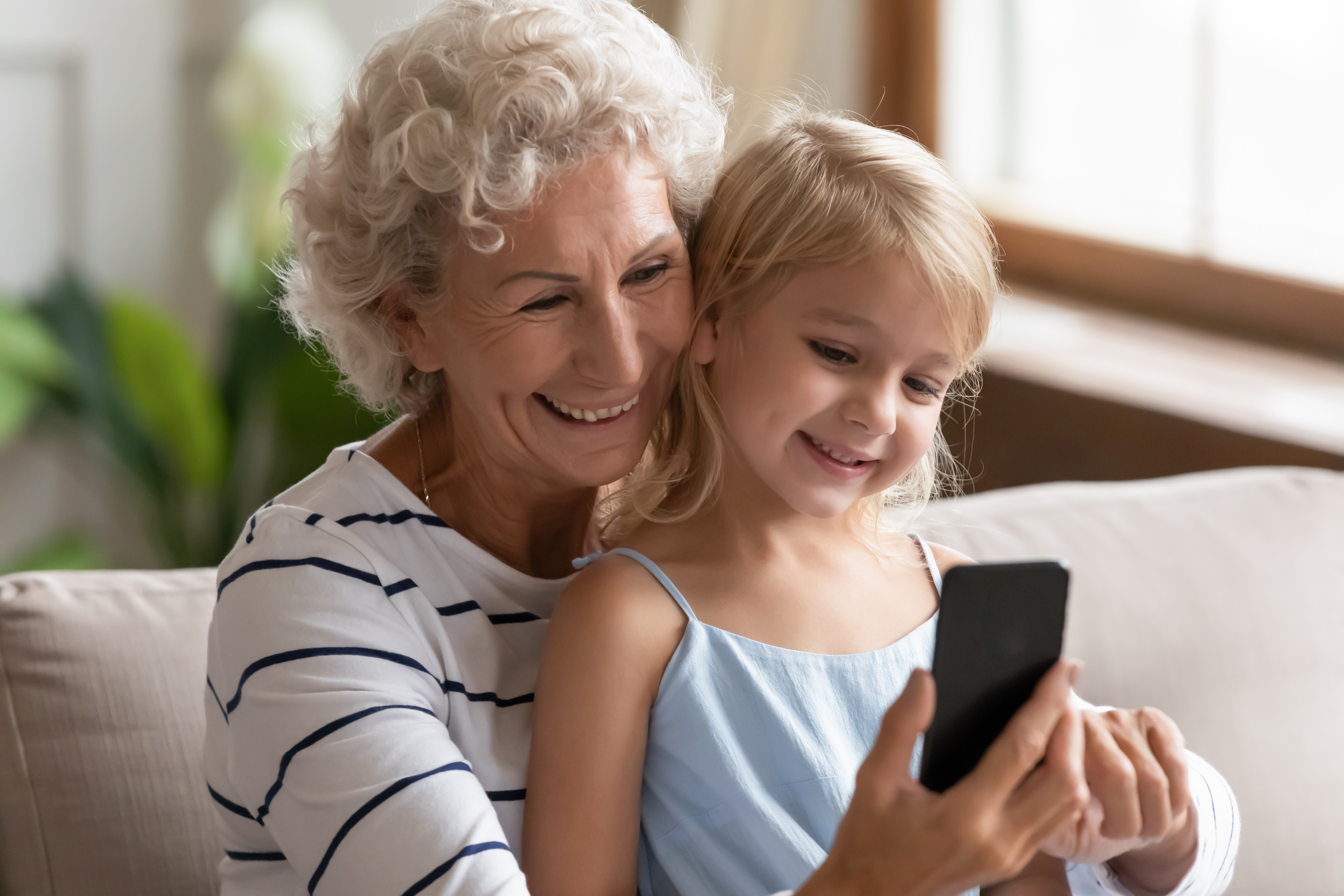 Oma und Enkelin schauen gemeinsam auf ein Handy
