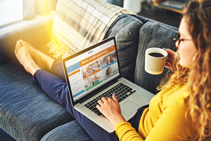 Eine Frau mit Laptop auf der Couch nutzt den eins Onlineservice