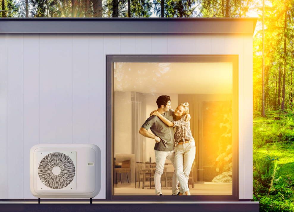 Mann und Frau stehen in ihrem Haus. Eine Wärmepumpe ist am Haus zu erkennen.