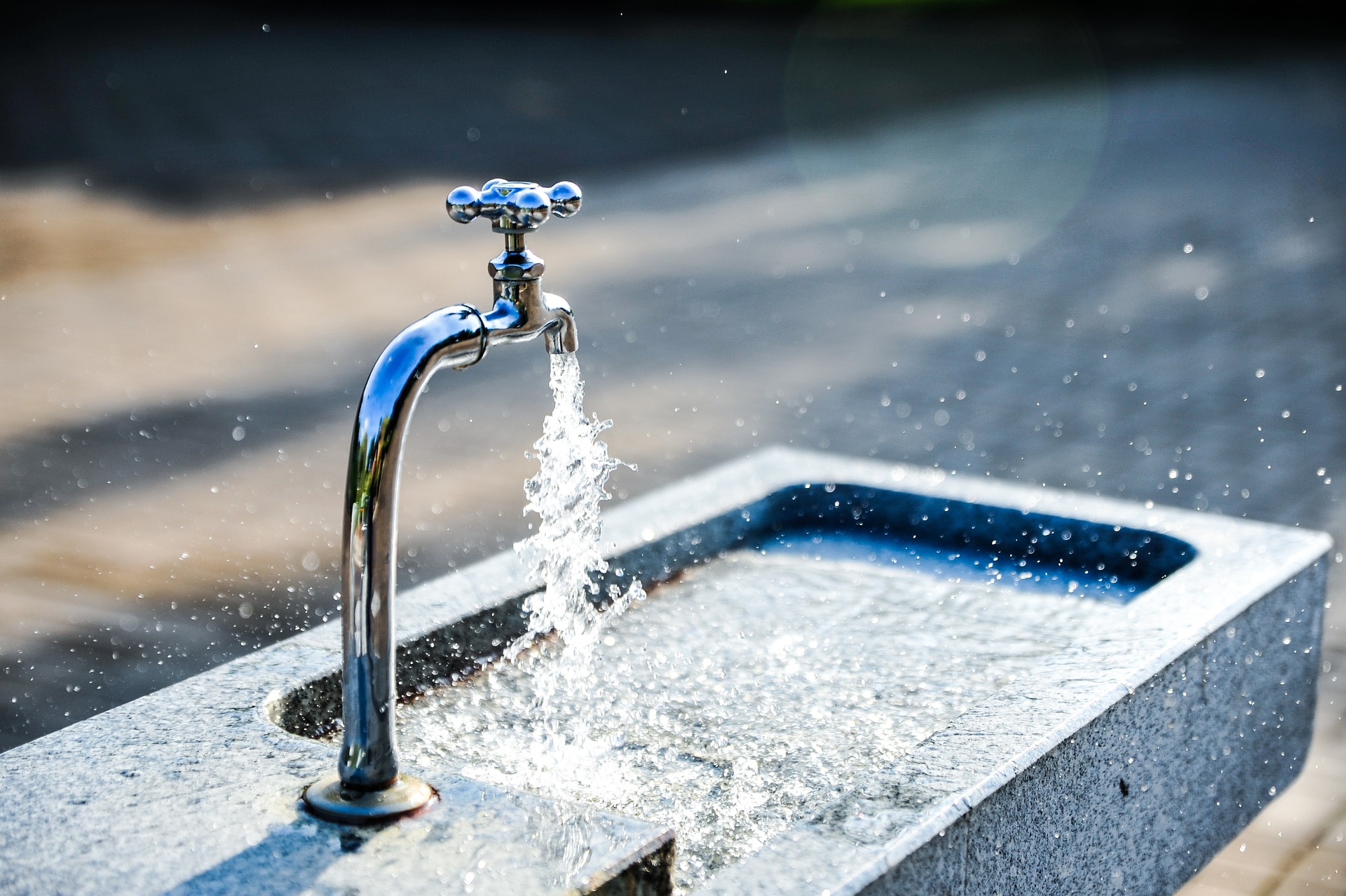 Wasserhahn aus dem Wasser in ein Wasserbecken fließt