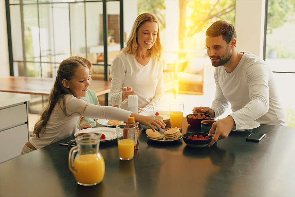 Familie sitzt am Tisch und isst Pfannkuchen