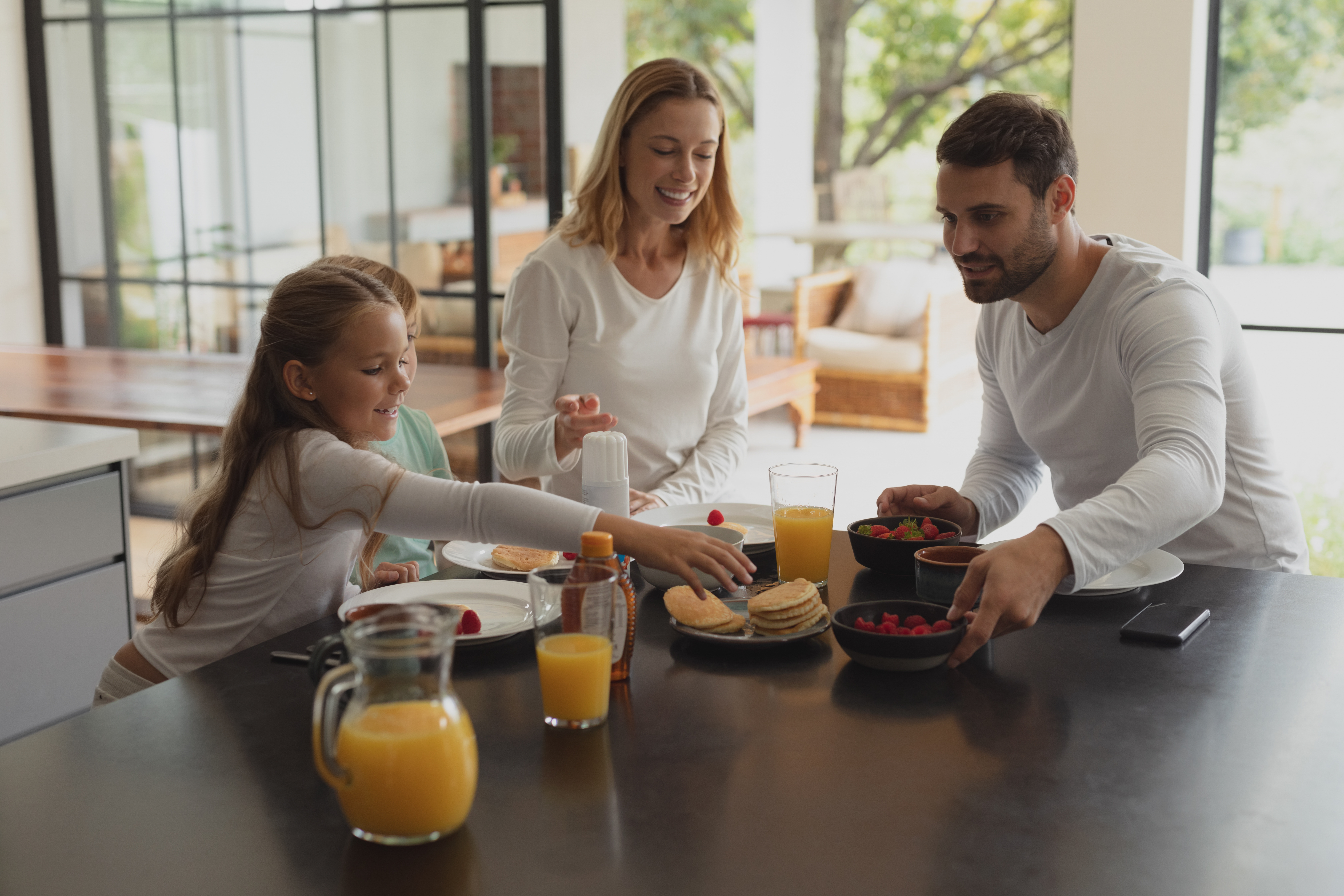 Familie sitzt am Tisch und isst Pfannkuchen