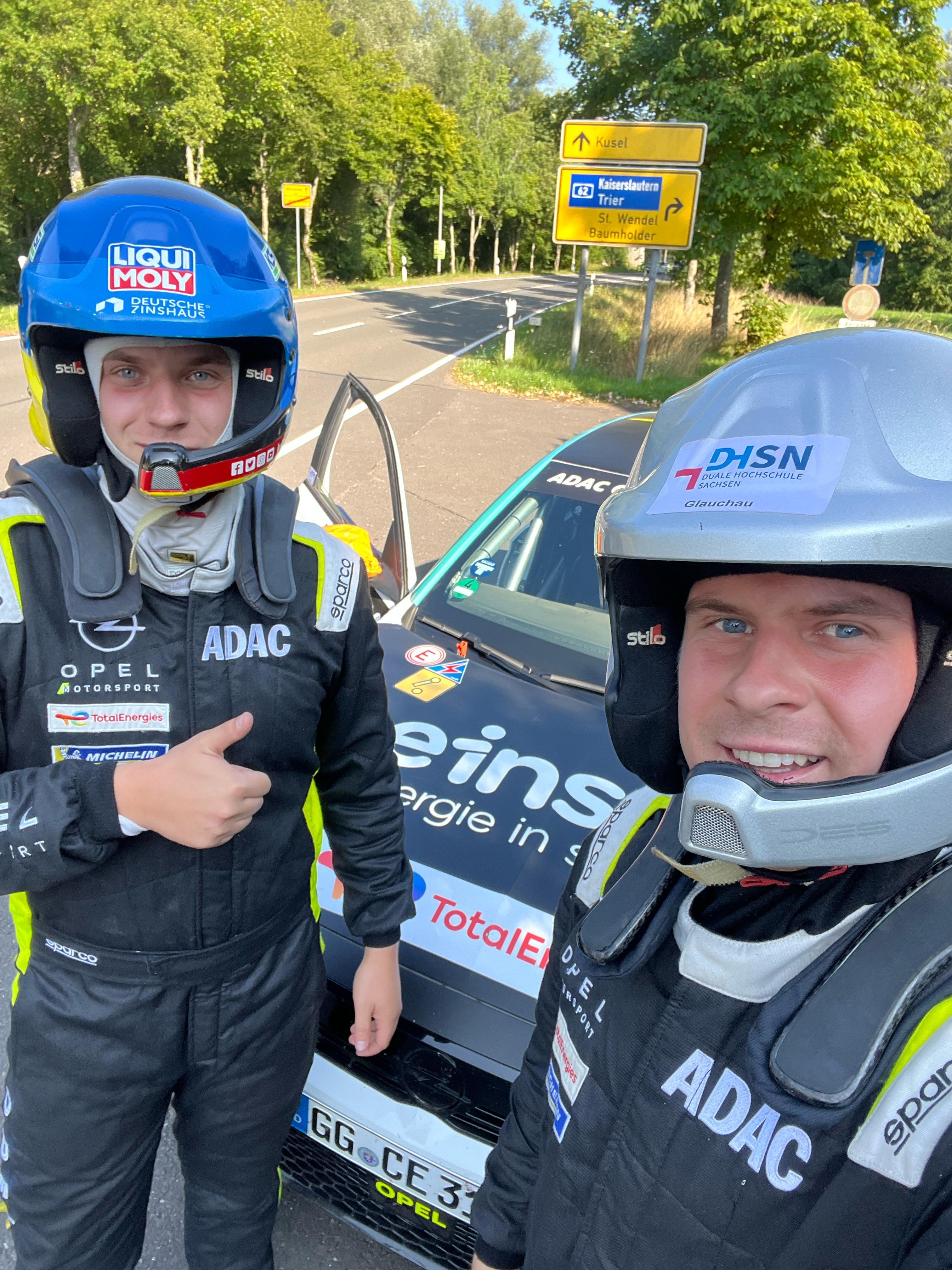 Aaron und Arwed in ihren Rallye-Anzügen, stehen vor ihrem Auto.