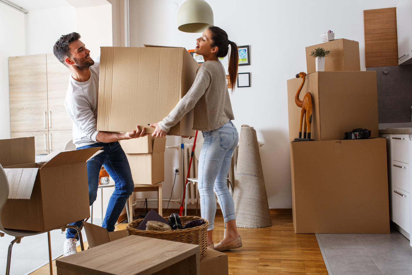 Paar trägt gemeinsam Umzugskiste durch die Wohnung