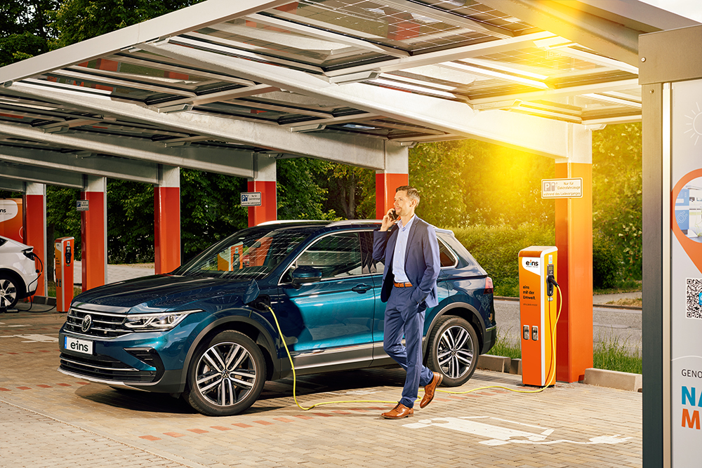 Business-Mann lädt Firmenwagen an E-Ladesäule