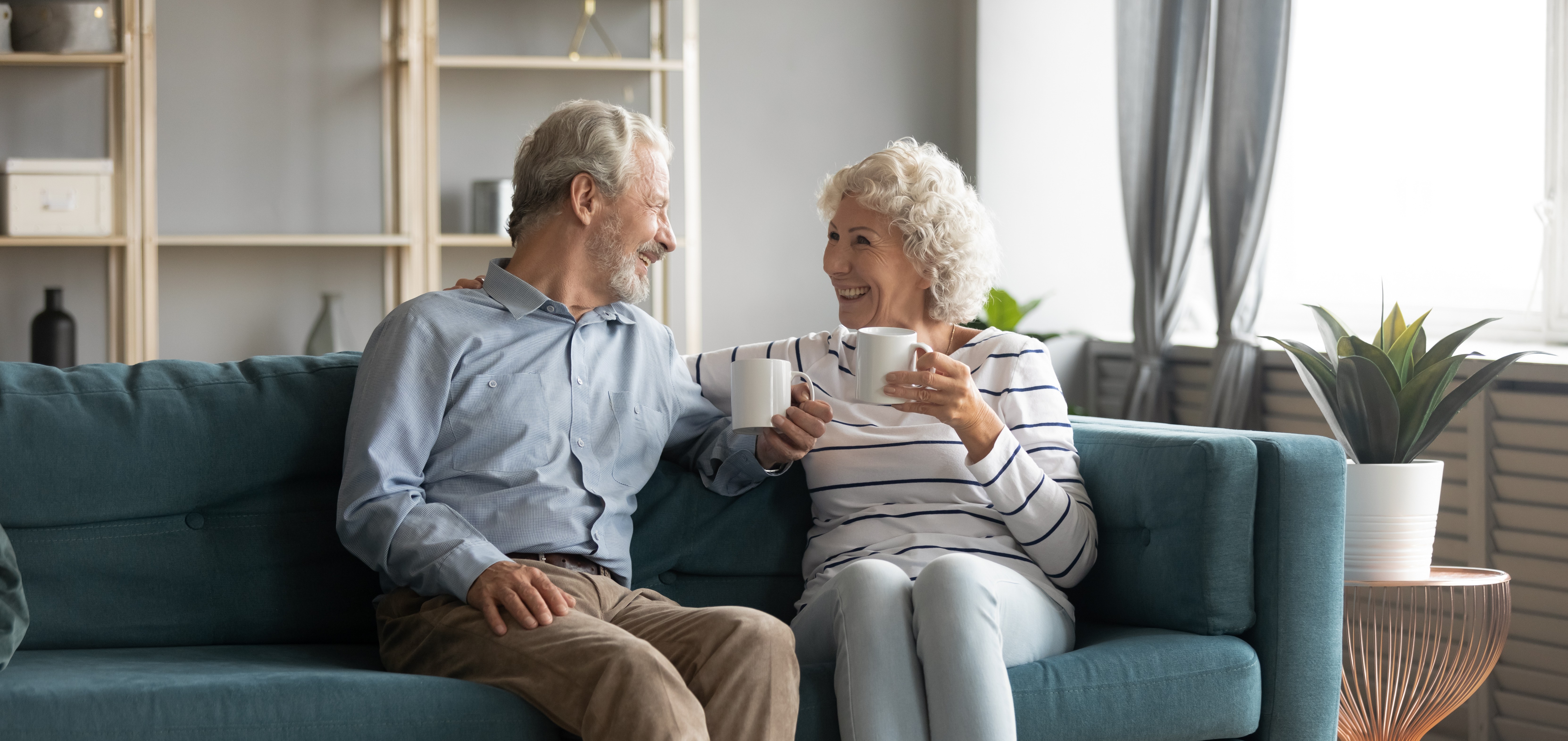 Rentnerehepar sitzt Kaffetrinkend auf einer Couch