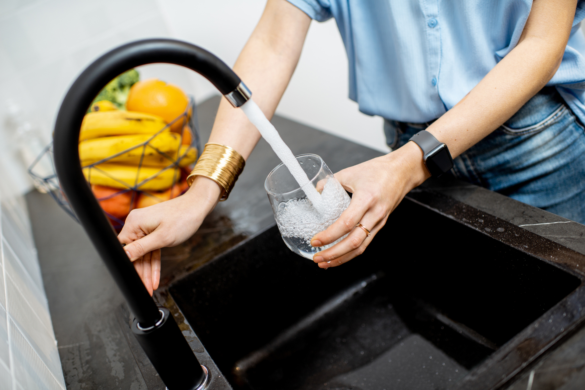 Frau füllt Glas mit Wasser aus dem Wasserhahn