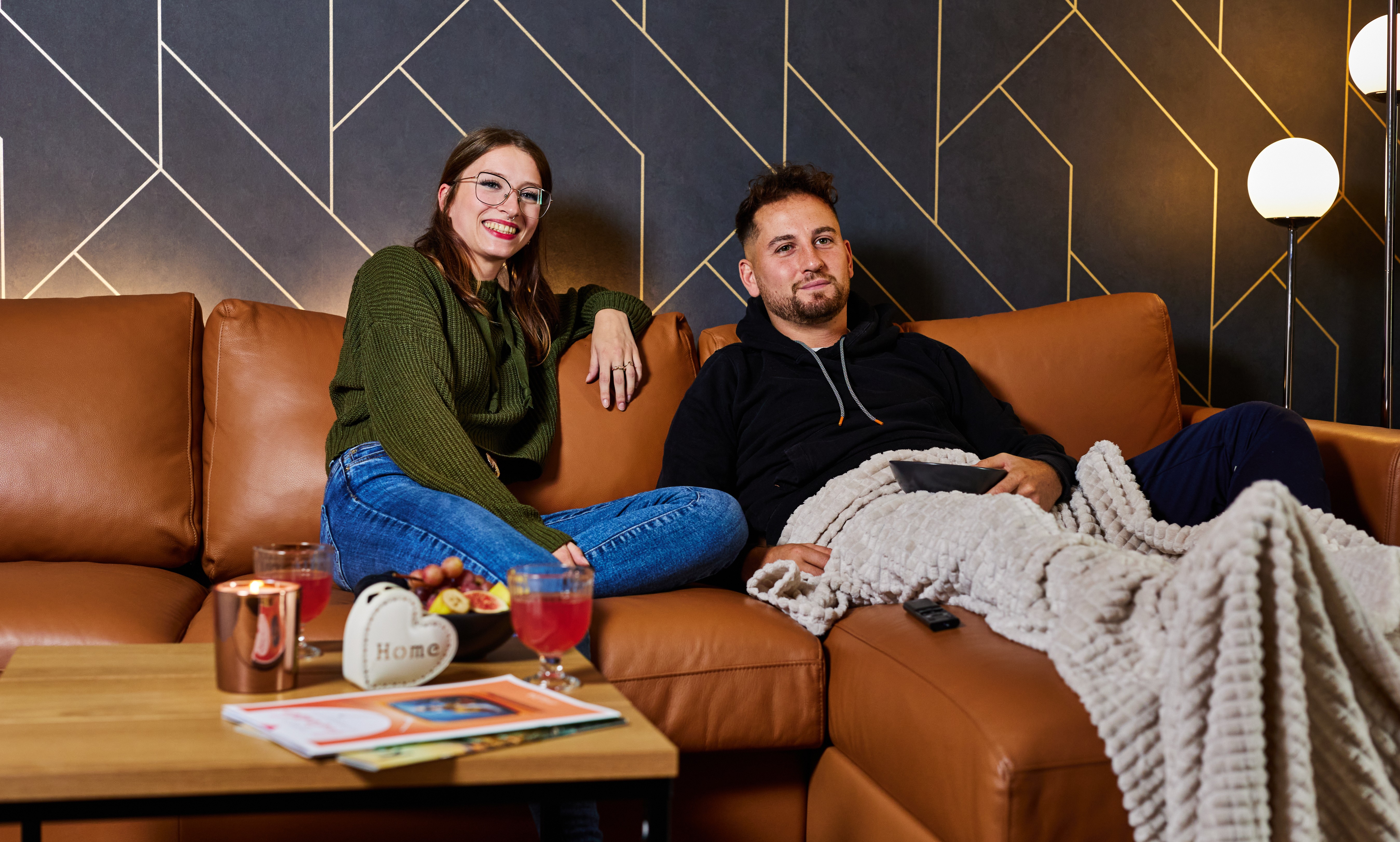 Man und Frau sitzen gemeinsam auf der Couch und schauen TV mit ihrem neuen Glasfaseranschluss