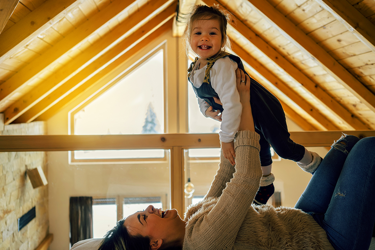Mama und Tochter spielen lachend auf dem Dachboden