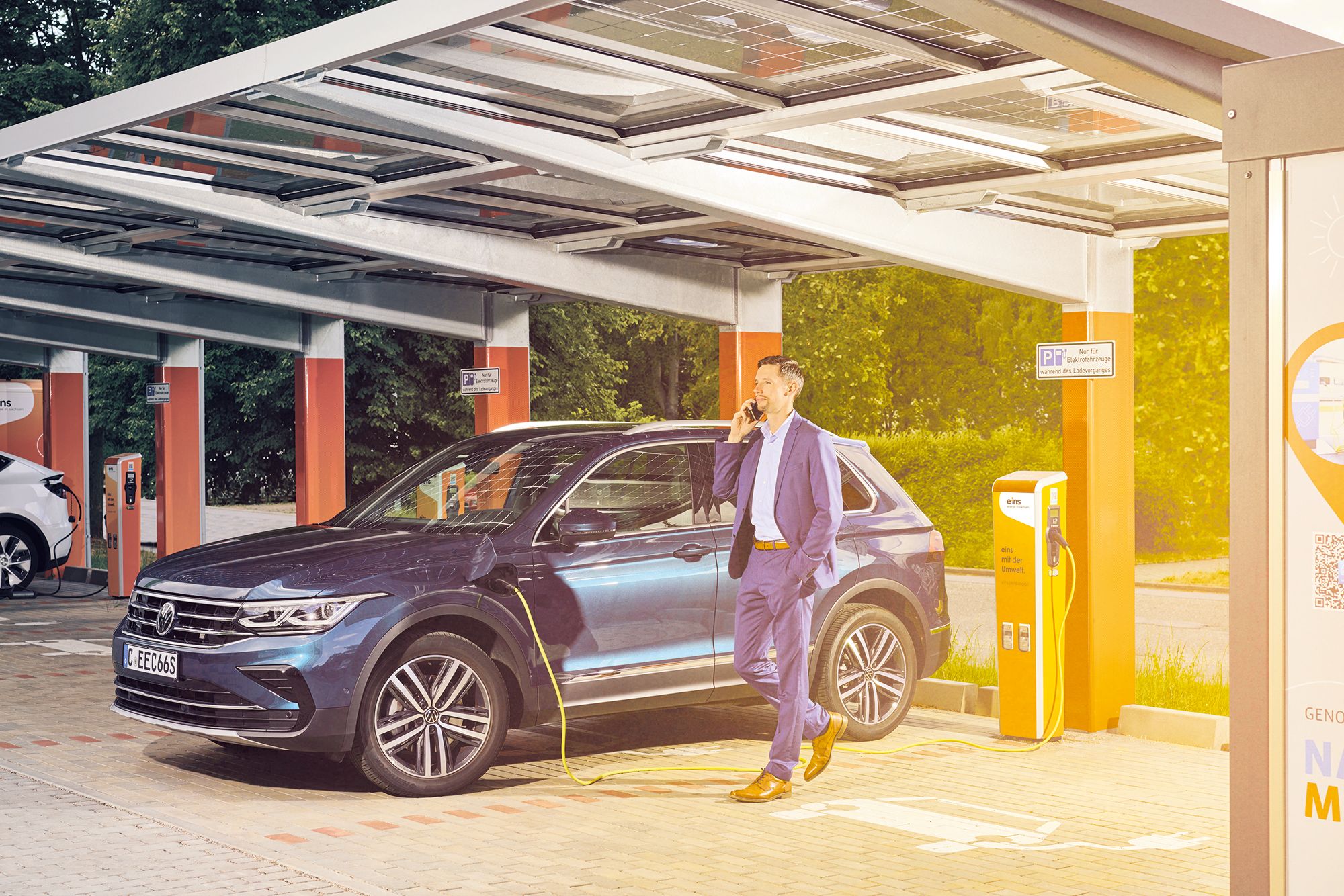 Business-Mann lädt Firmenwagen an E-Ladesäule