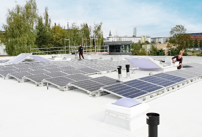 Photovoltaikanlage auf einem Flachdach die von 2 Technikern installiert wird.