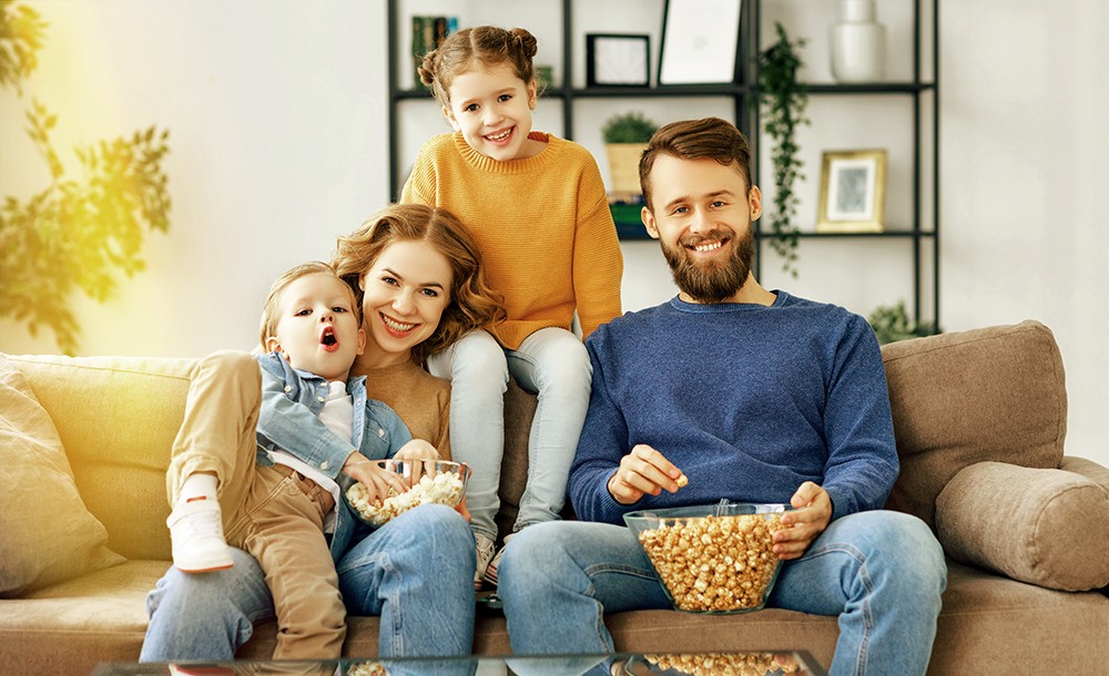 Eine Familie sitzt auf dem Sofa und schaut TV.