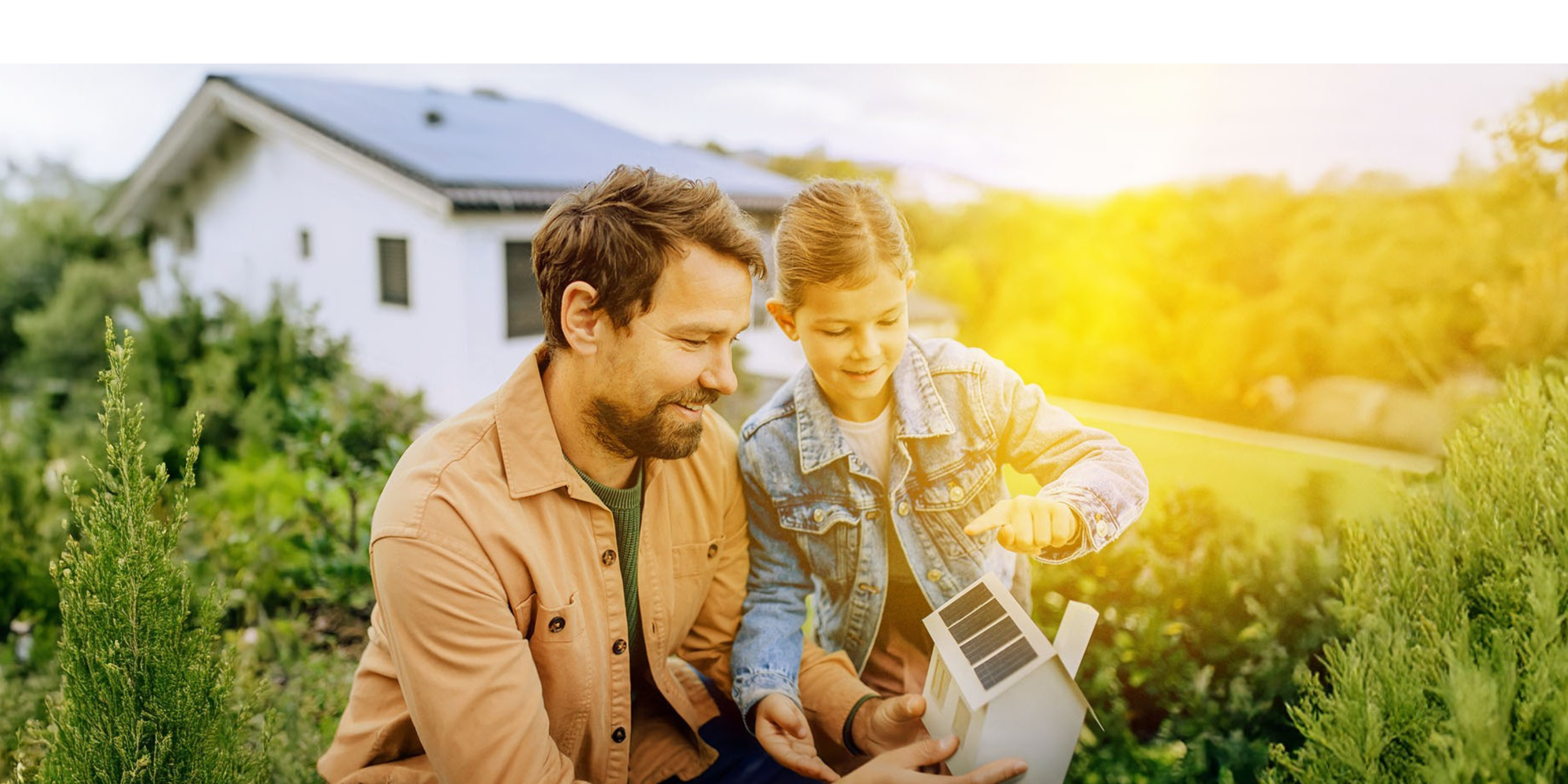 Papa erklärt Tochter Solar im Garten anhand eines Papphauses