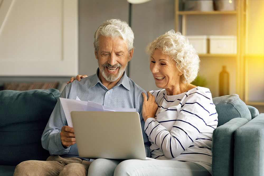 Ehepaar sitzt auf dem Sofa und sucht neuen Vertrag.