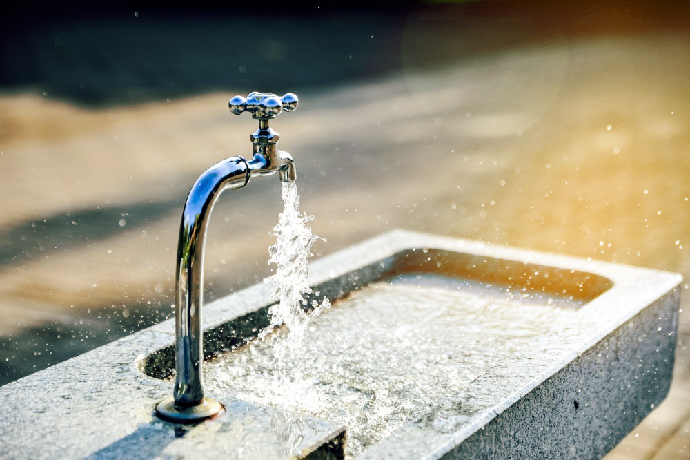 Wasserhahn aus dem Wasser in ein Wasserbecken fließt