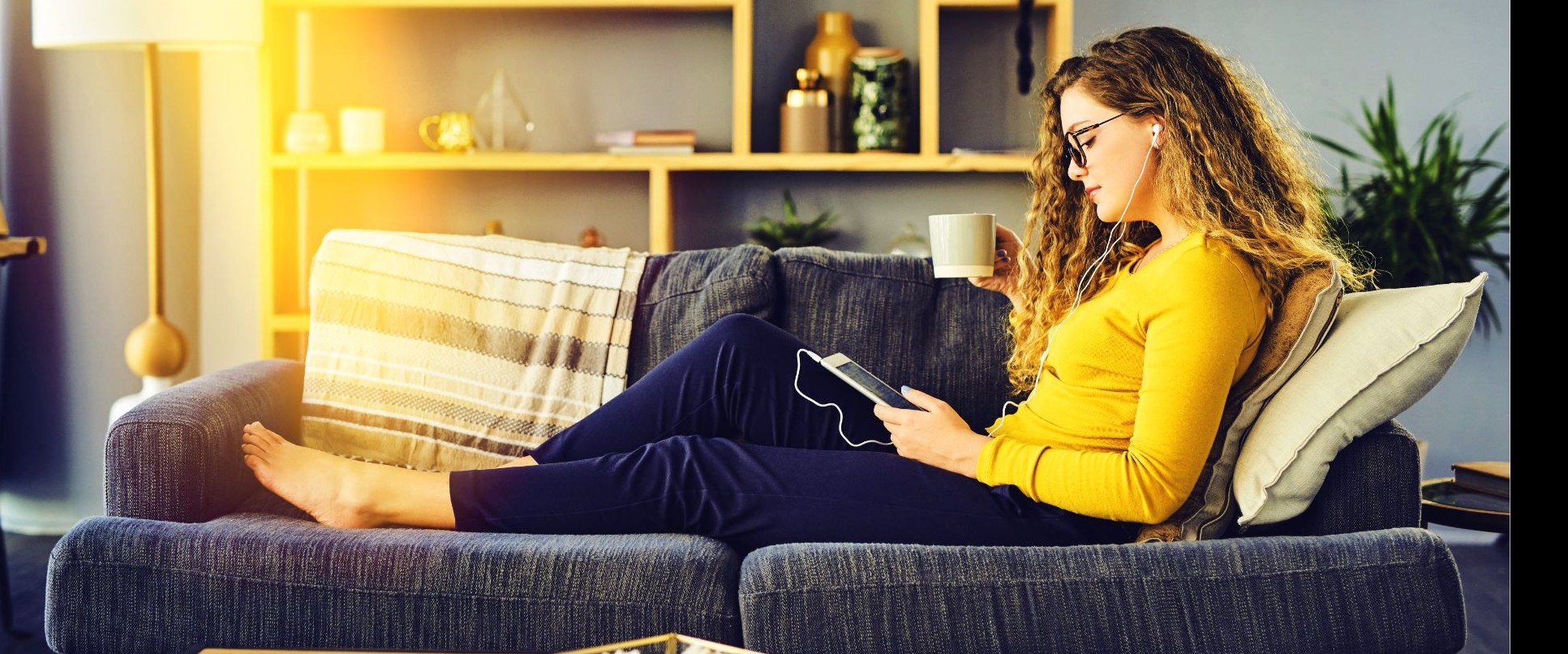 Eine Frau liegt auf ihrem Sofa und checkt die Service-Zeiten auf der eins-Website