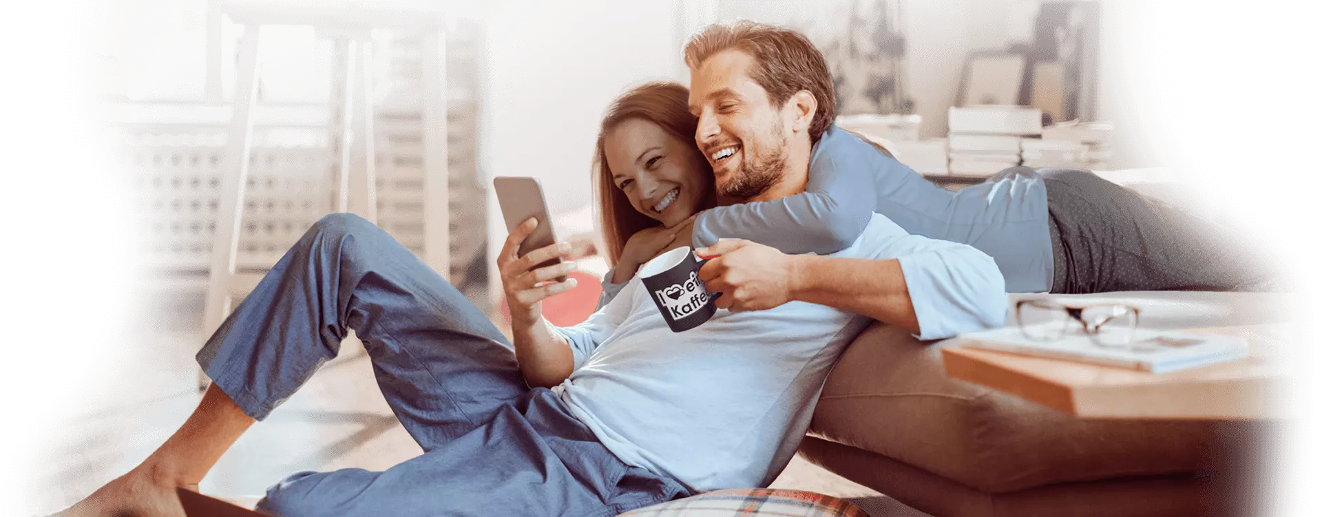 Ein Mann und eine Dame schauen gemeinsam auf ein Handy und lachen dabei