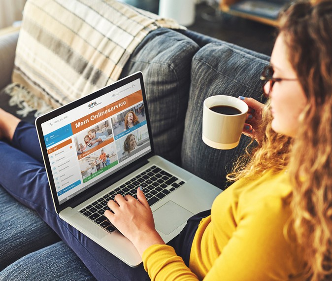 Eine Frau mit Laptop auf der Couch nutzt den eins Onlineservice