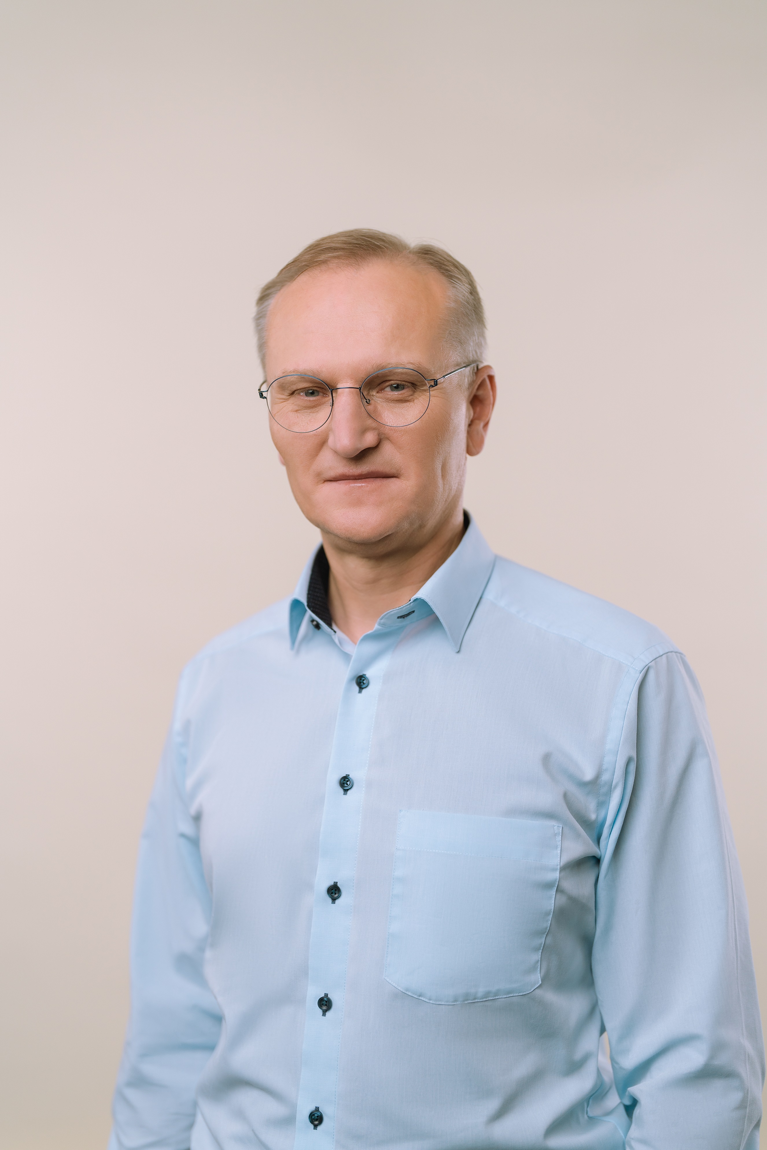 Portrait von Roland Warner in blauem Sakko und gelber Krawatte