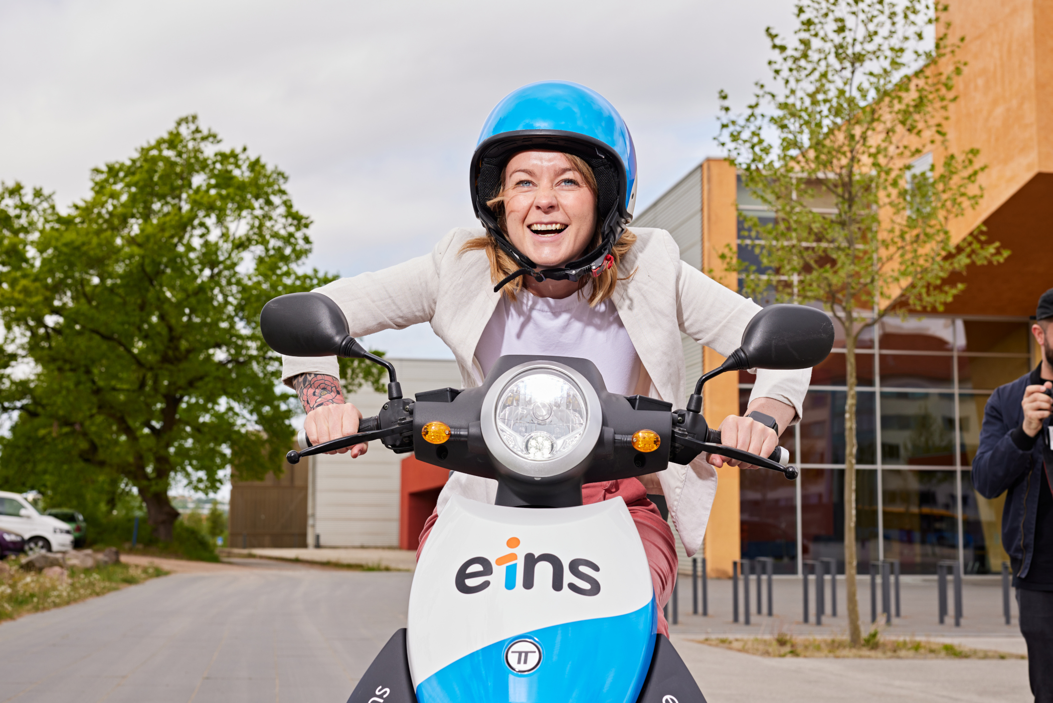 Eine lachende Dame auf einem eins E-Roller