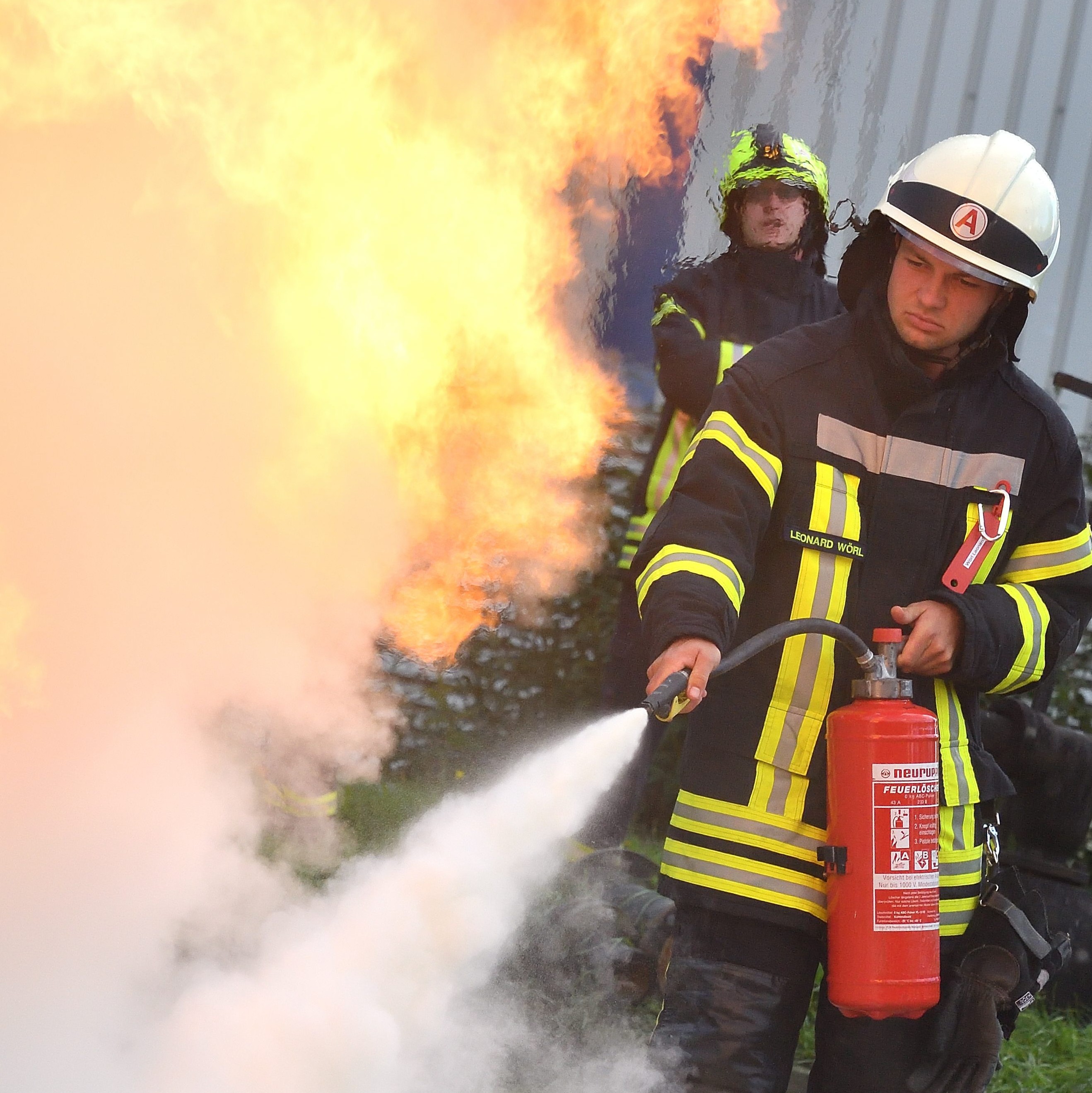 Feuerwehrmann löscht Flamme mit Feuerlöscher