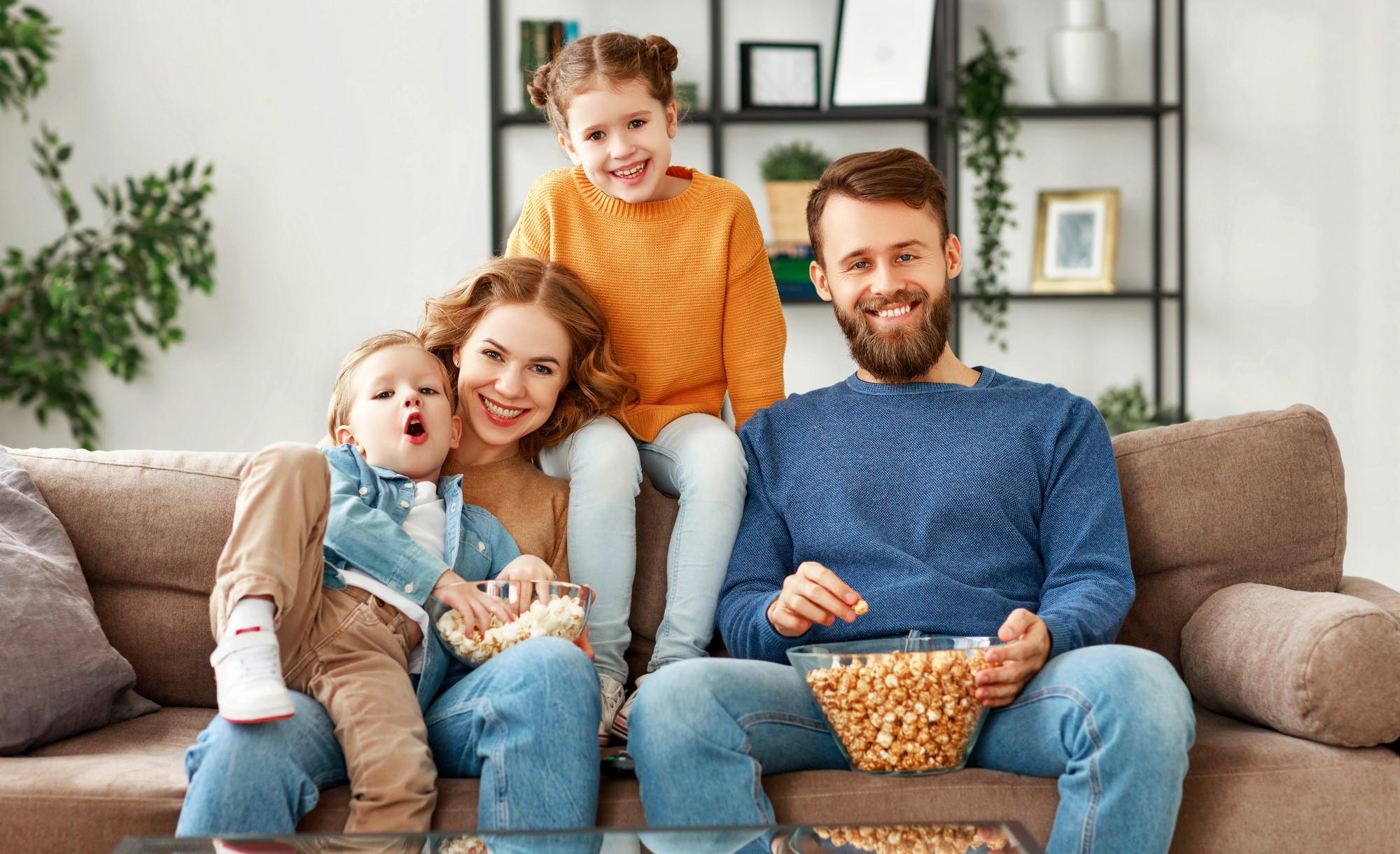Eine Familie sitzt auf dem Sofa und schaut TV.