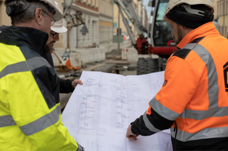 3 Baustellenarbeiter begutachten den Bauplan